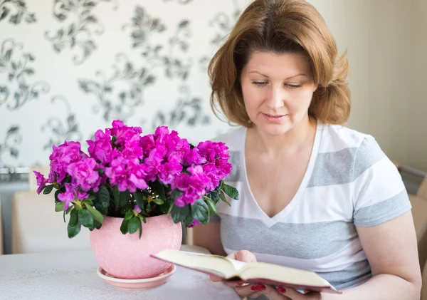 Woman reading a book while sitting at  table