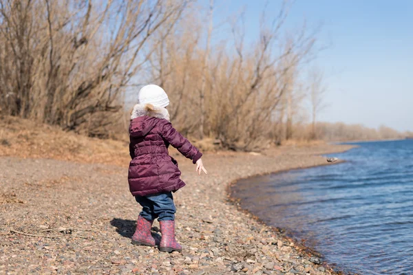 Girl throwing stones into river