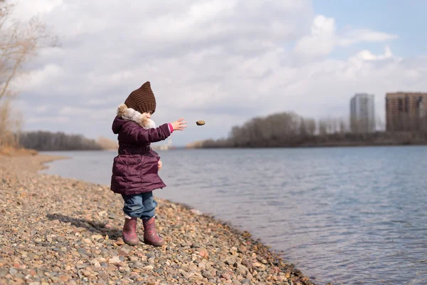Girl throwing a stone into river
