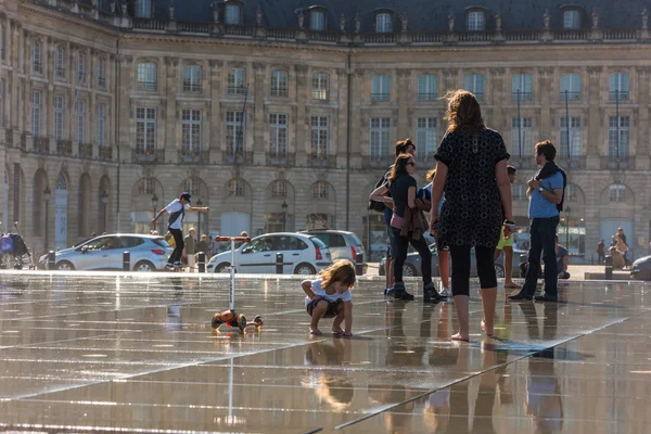 People having fun in a mirror fountain in Bordeaux, France