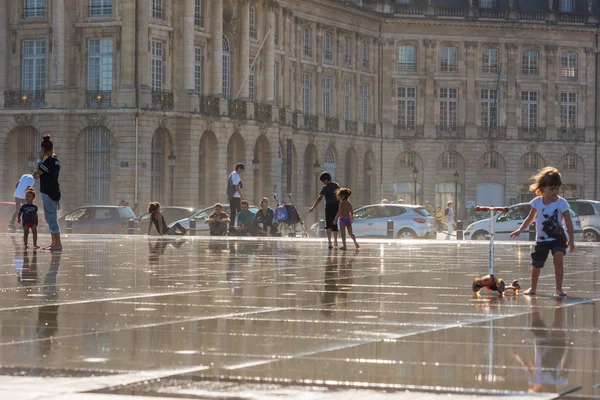 People having fun in a mirror fountain in Bordeaux, France