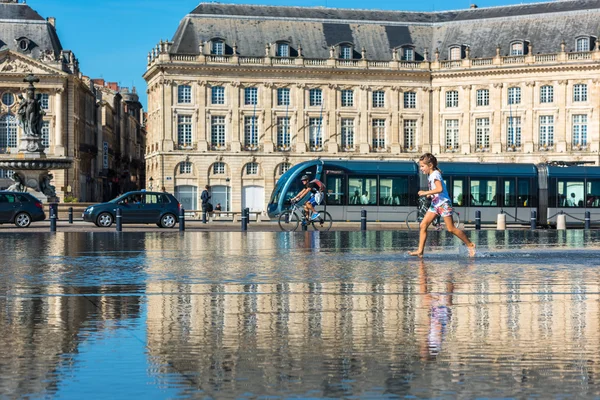 People having fun in a mirror fountain in Bordeaux, France