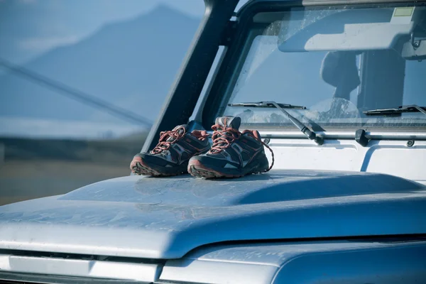 Trekking shoes are drying on a dirty 4wd car bonnet