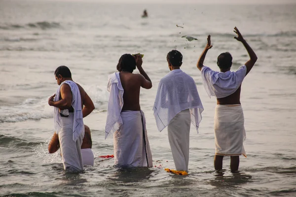 VARKALA, INDIA - DEC 15, 2012:  Pilgrims walk down to the sea to offer puja. This is a holy place. Pilgrims come here to take a holy dip in the holy waters of the beach.