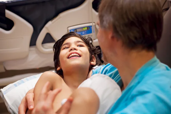 Father holding disabled sick son on lap in hospital