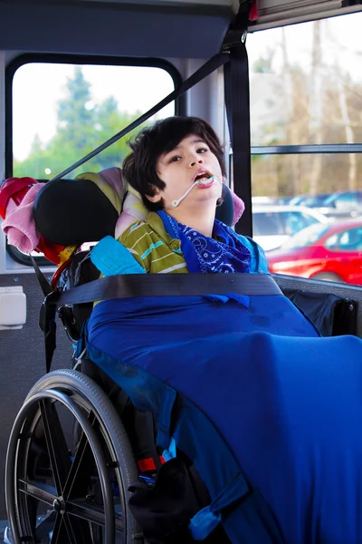 Disabled eight year old boy in wheelchair buckled on school bus