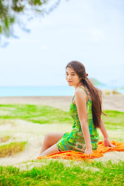 Teen girl in green sundress at beach looking over shoulder