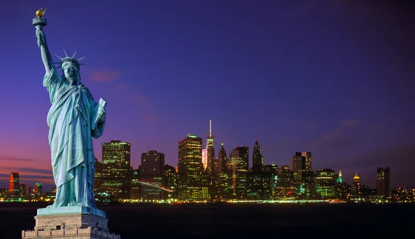 Manhattan skyline at night and Statue of Liberty.