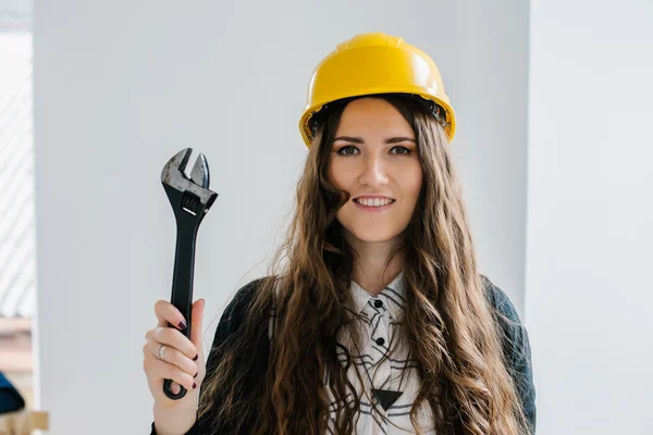 Girl in a helmet holding a wrench