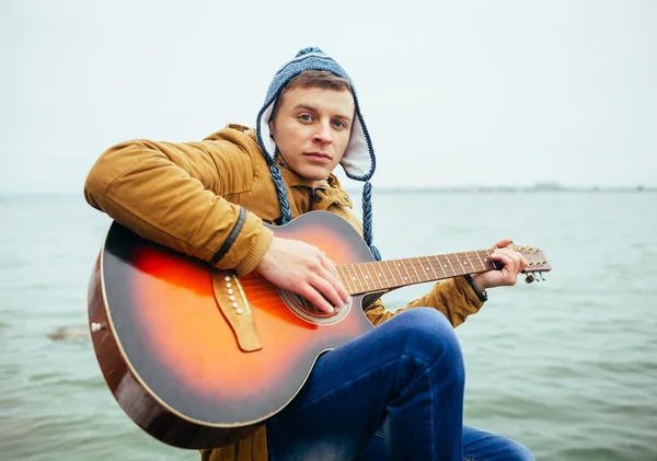 Man playing on guitar at the lake