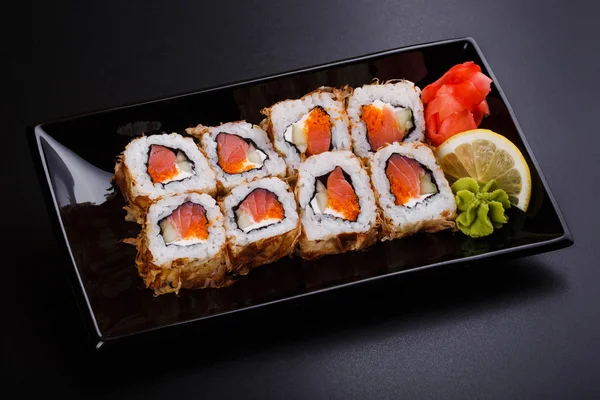 Fresh sushi roll with smoked salmon, on black dish