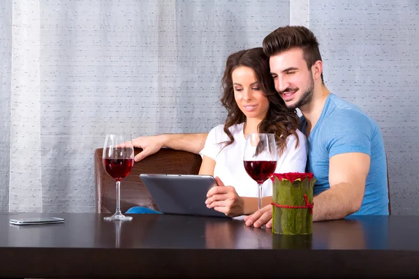 Young couple using a Tablet PC while having a glass of wine