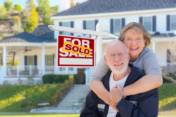 Senior Adult Couple in Front of Real Estate Sign, House