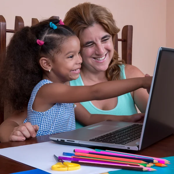 Small multiracial girl and her mother working on a laptop comput