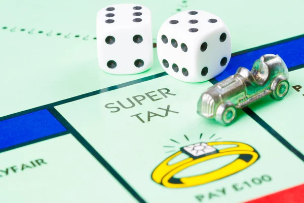 Dice and token next to SUPER TAX in Monopoly game