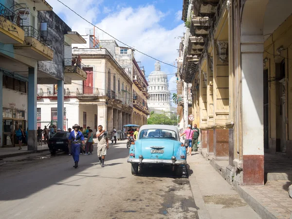 Street scene in Old Havana with people and an old american car