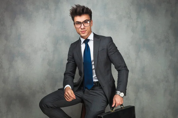Seated young business man with glasses holding a briefcase