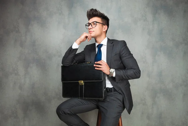 Business man with glasses and holding briefcase is thinking