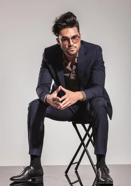 Elegant man with glasses sitting on chair