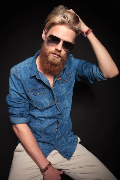 Fashion man in blue shirt sitting and fixing his hair