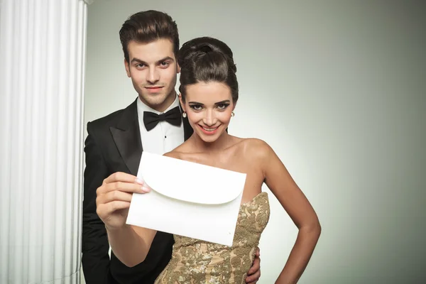 Happy young couple presenting an invite to their wedding