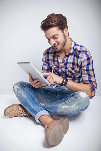 Young fashion man sitting while using a tablet computer