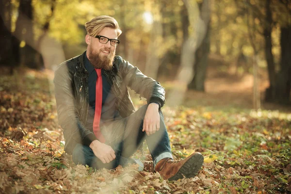 Young casual fashion man sitting in the park