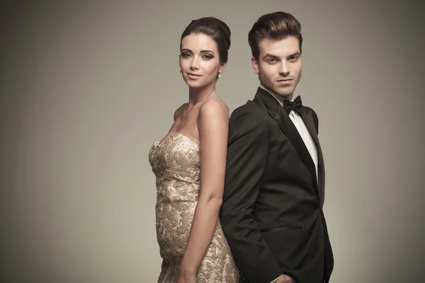 Elegant man and woman standing back to back