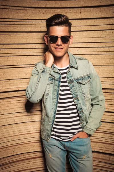 Relaxed man in jeans jacket and sunglasses poses