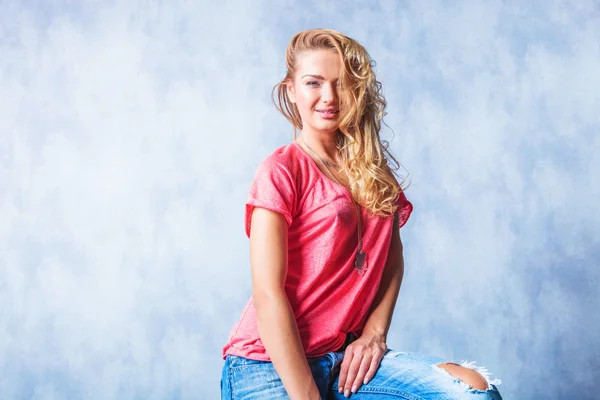 Blonde girl smiling and sitting with rugged jeans and messy hair