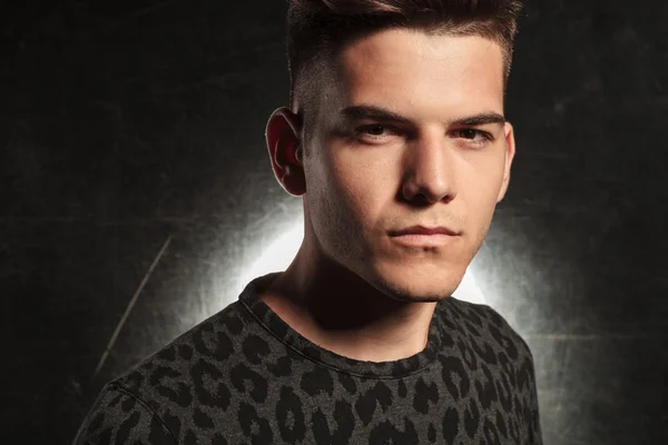 Young man in leopard print looking at the camera in studio backg