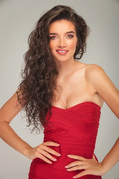 Model in red dress touching her waist while posing