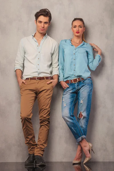 Couple standing in studio posing with hands in pockets