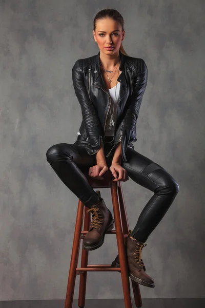 Attractive rocker woman in leather posing seated in studio