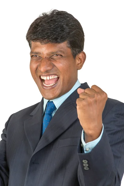 A thrilled Indian or South Asian business executive in a suit cheering a win or victory with a big shout and clenched fist. Isolated on white background.