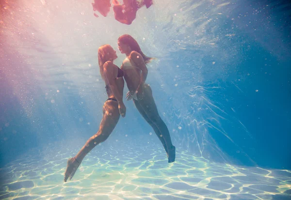 Two women swimming underwater in the swimming pool