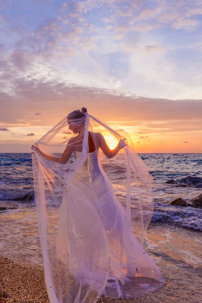 Bride posing showing her wedding dress on the beach