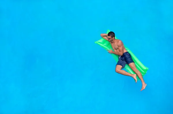 Man relaxing on the air bed in the swimming pool.
