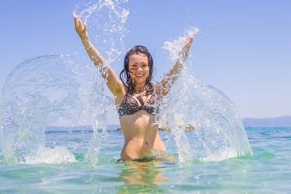 Young woman in the sea splashing water
