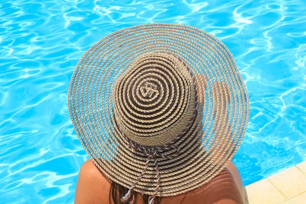 Young woman sitting on the ledge of the pool.