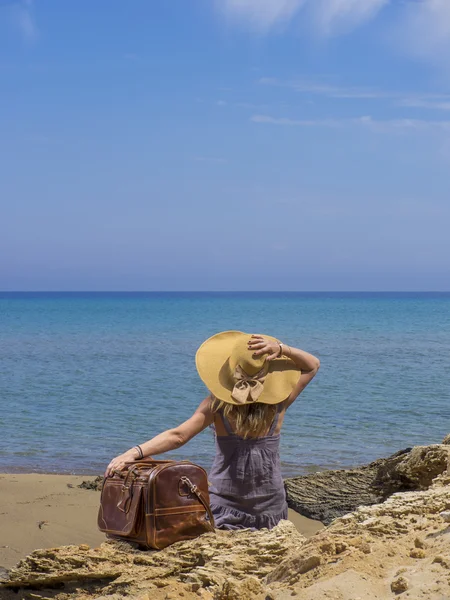 Woman with leather travel bag on the beach