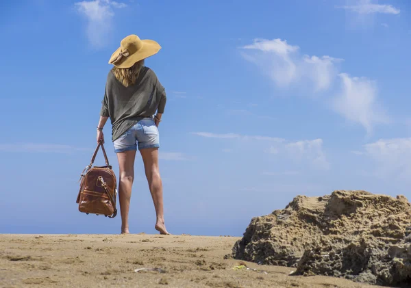 Woman with leather travel bag on the beach