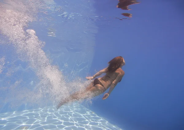 Female swimmer after jumping with air bubbles trail