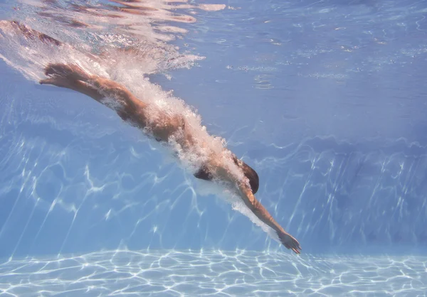 Female swimmer after jumping with air bubbles trail