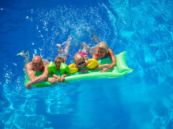 Family Outside Relaxing In Swimming Pool