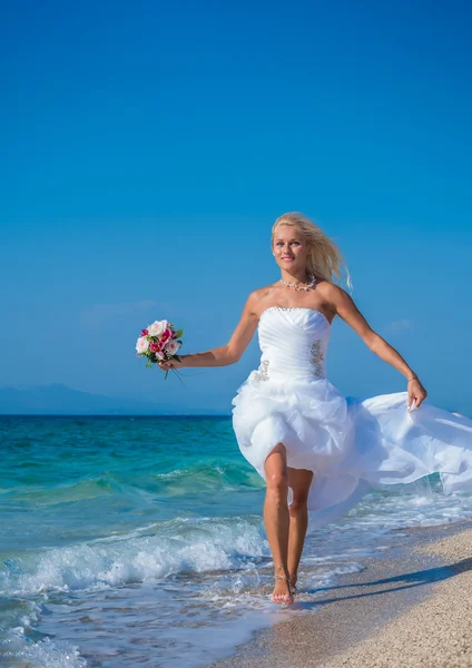 Young bride in wedding drees having fun on the beach