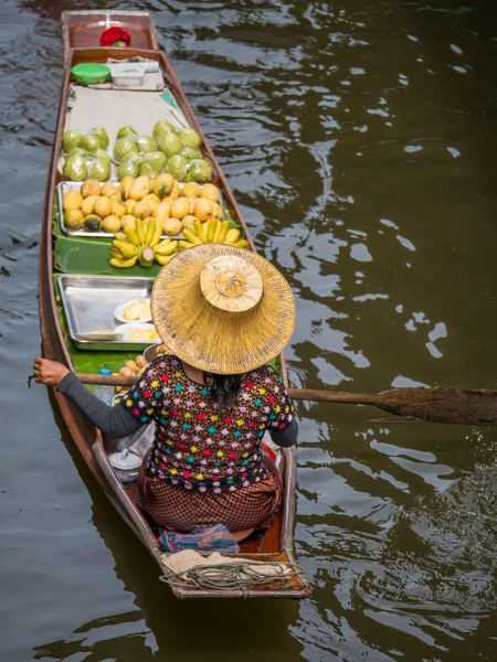 Traders selling vegetables and fruits by sailing a boat in a fl
