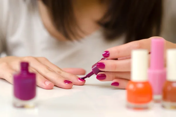 Manicure nail paint purple color on white table at home