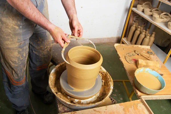 Craftsman making vase on the pottery wheel in pottery workshop