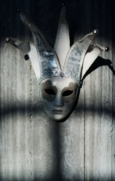 Jester mask hanging on the concrete wall spooky shadows dancing